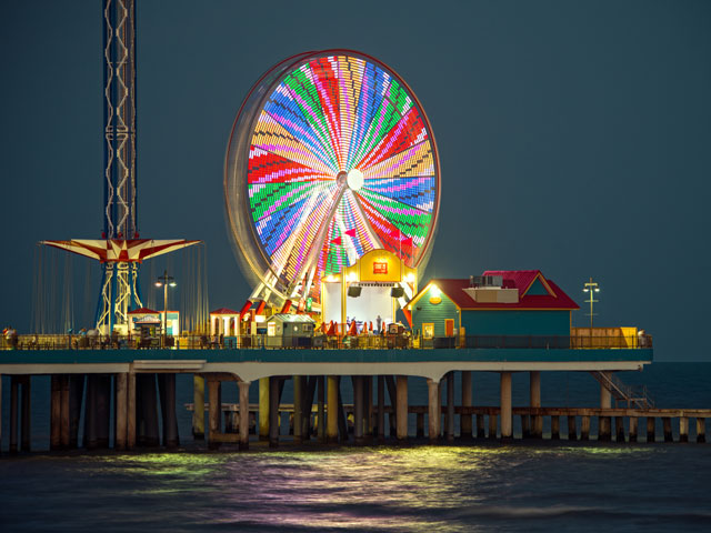 The shining neon lights of Galveston's Pleasure Pier illuminate the night sky.