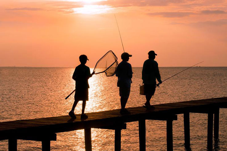 A man leads two youngsters on a fishing pier at dawn in Rockport, Texas. 