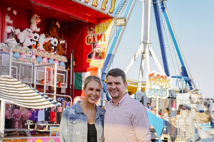 Couple standing in front of carnival rides