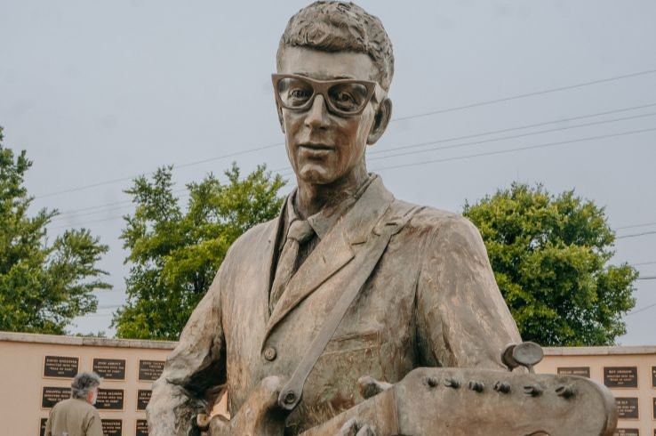 The bronze Buddy Holly statue at the Buddy Holly Center in Lubbock, with the West Texas Walk of Fame plaques visible in the background.