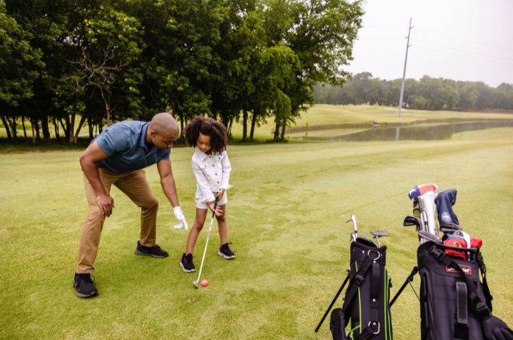 A father helping his daughter with her swing