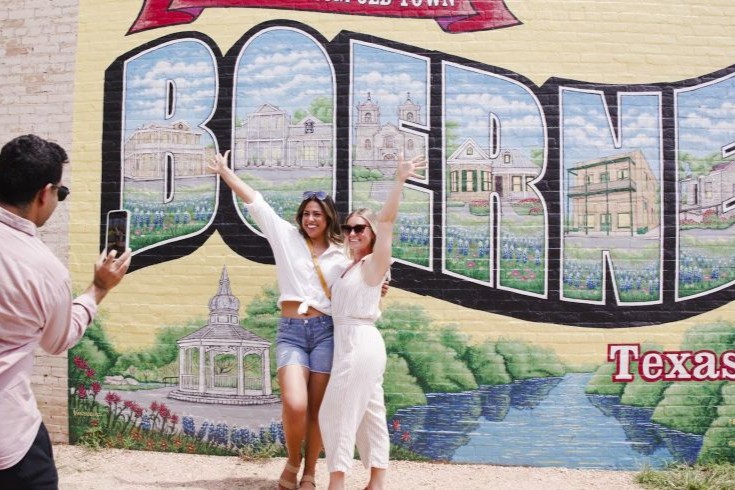 Friends posing in front of the Boerne mural on the Hill Country Mile