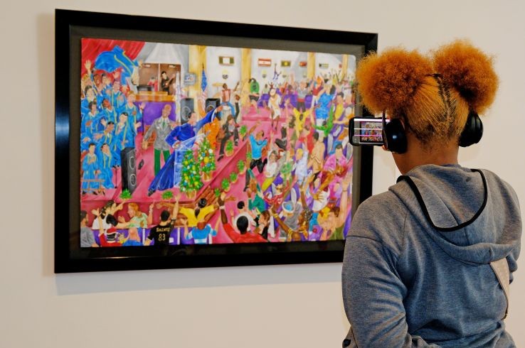 Young woman takes a picture of a painting