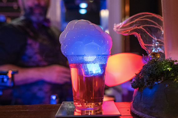 A signature mocktail with bubbling smoke and a glowing ice cube sits on the bar at The Magic Saloon in San Antonio.