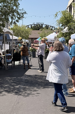Visitors browse white vendor tents along a closed downtown street during the Winnsboro Festival of Books, with a decorative archway and string lights overhead.
